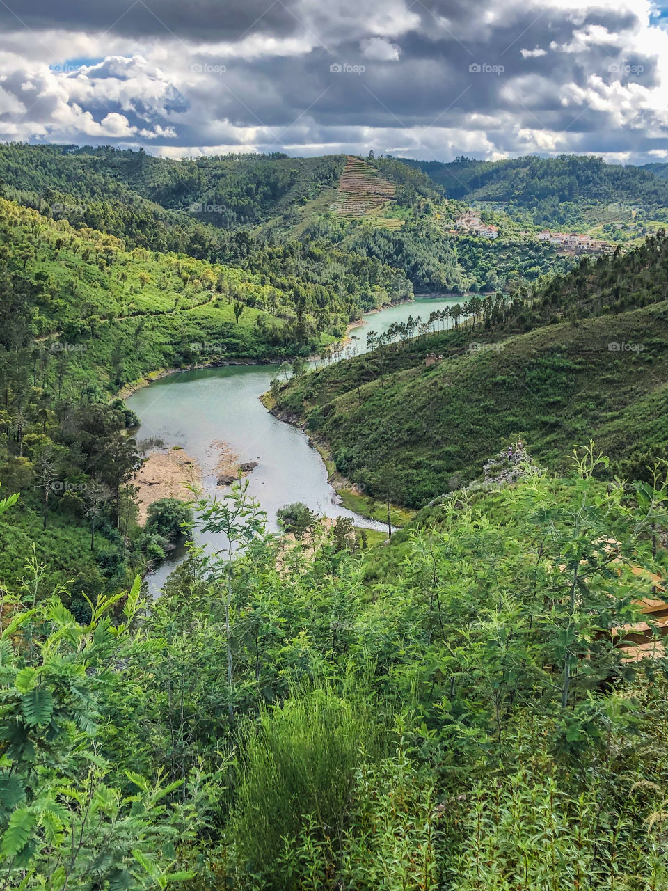 The river Zêzere as it winds off to Vila de Rei, in Central Portugal. The landscape is green and luscious and there are some clouds but otherwise sunny on this spring day.