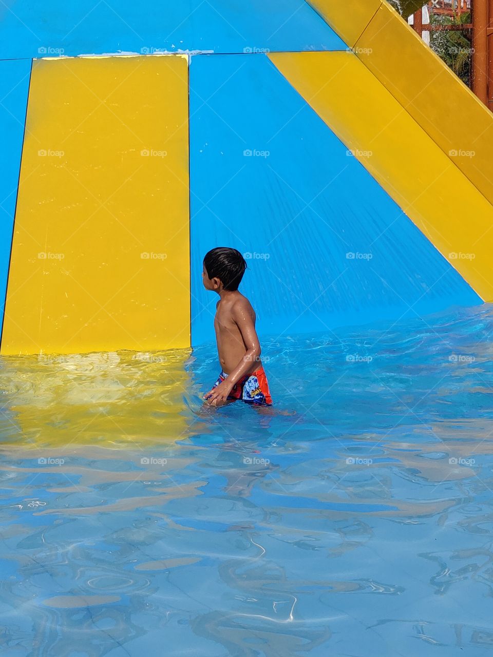 small kid inside water in an amusement park or water park in summer