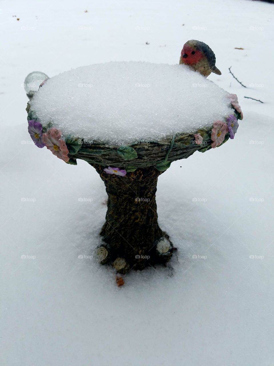 Snow on a birdbath sculpture