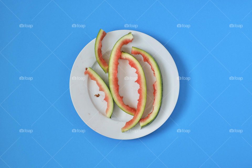 Directly above view of watermelon rind on porcelain plate isolated on blue background. 