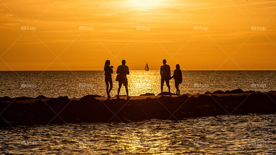 silhouette of couples walking on the pier during the golden hour of sunset