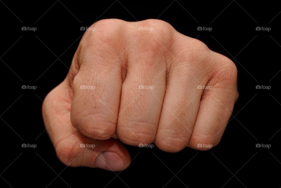 Hand folded into a fist on a black background