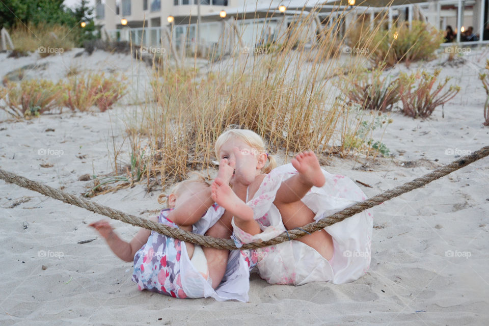 Two young sisters enjoying the beach falling down on the sand. Alcudia, Majorca, 
This picture is on of three pictures were the both fal back in the sand.