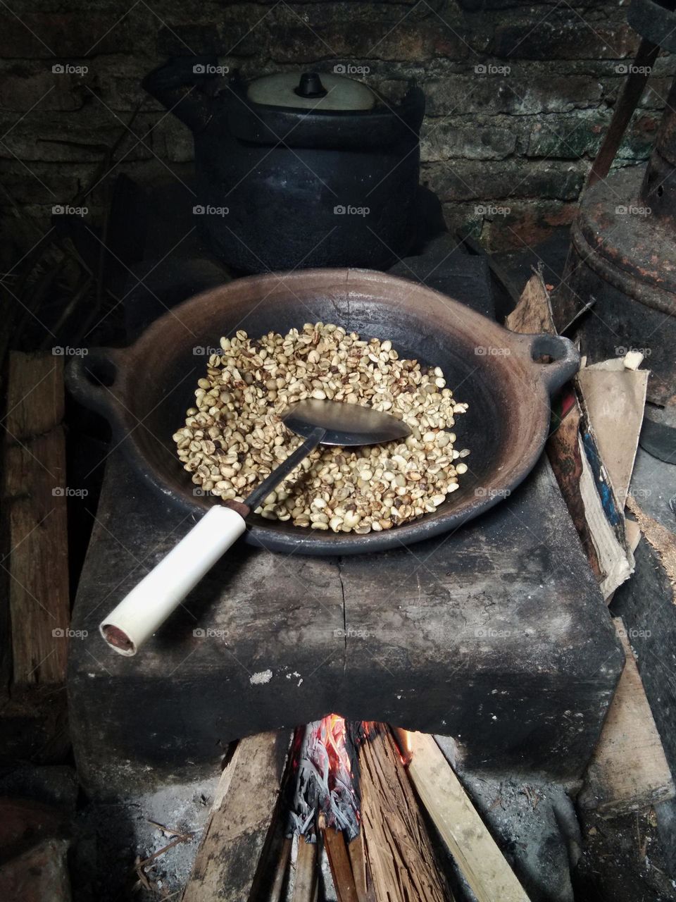 cooking or roasting coffee beans on the fireplace.  the frying pan made from clay material