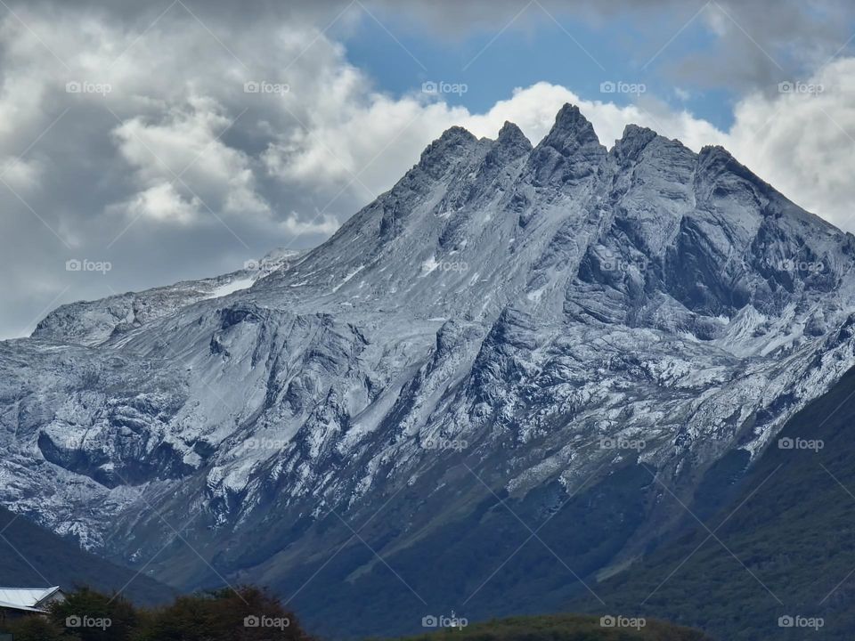 close up of a mountain with snow and cloudy sky