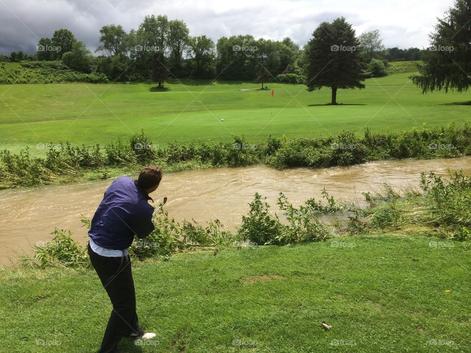 Golf swing over muddy water. A wet day on a PA golf course