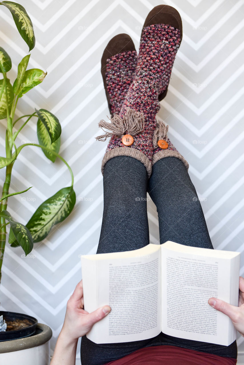 Woman's legs propped up against a wall while reading a book