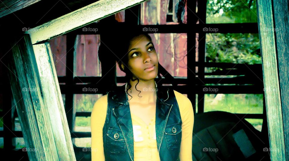 Teenager girl standing in front of wooden barn
