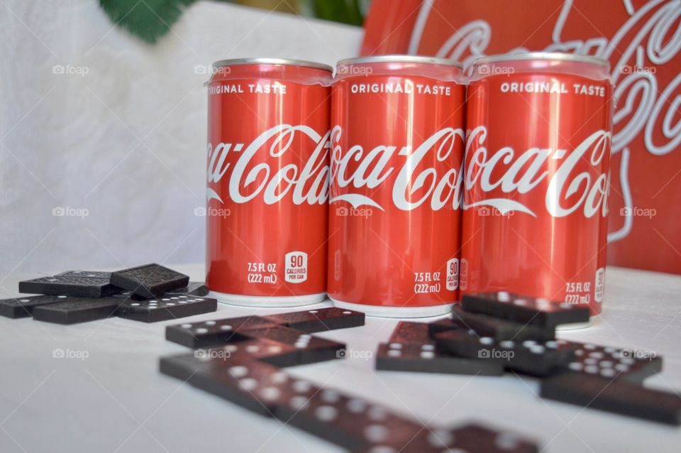Six pack of Coca-Cola cans with dominoes