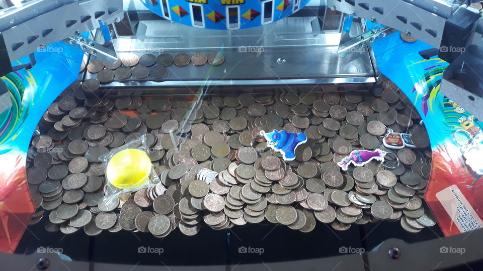 2p coins and prizes inside of an arcade penny pusher machine.