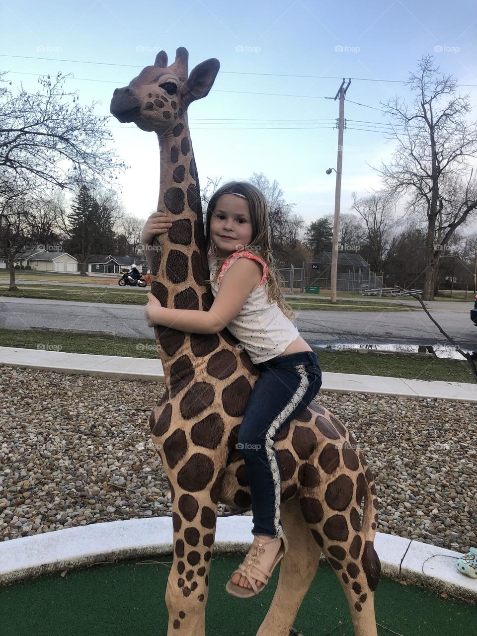 Lylliona sitting on the giraffe statue at the park 