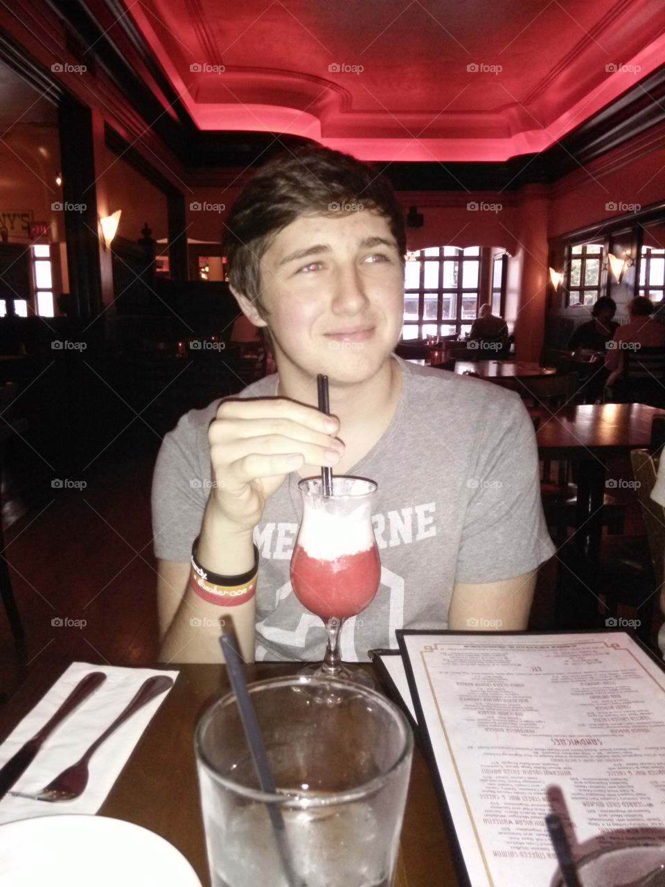 Teenage Diner. Mother's view from across the table of her teenage son, drinking a nonalcoholic frozen beverage.