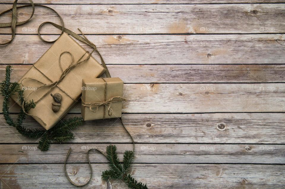 Monochromatic flat lay of naturally wrapped brown Christmas gifts on a wooden floor 