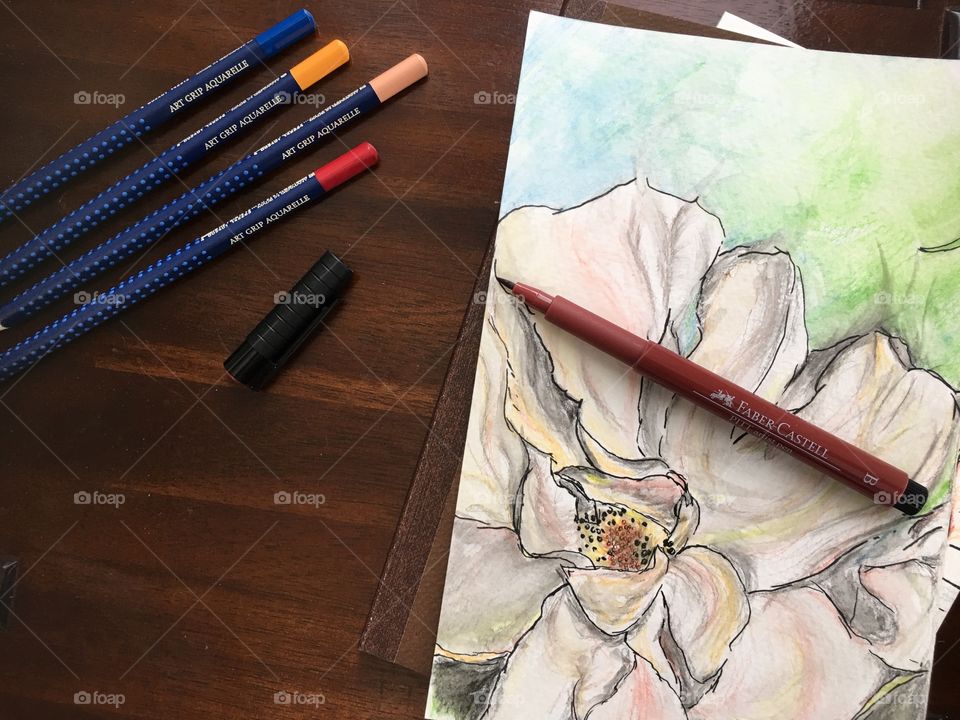 Watercolor sketch of flower on Wood table and sketchbook with colorful Faber-Castell PITT Artist pens and Art Grip Pencils 