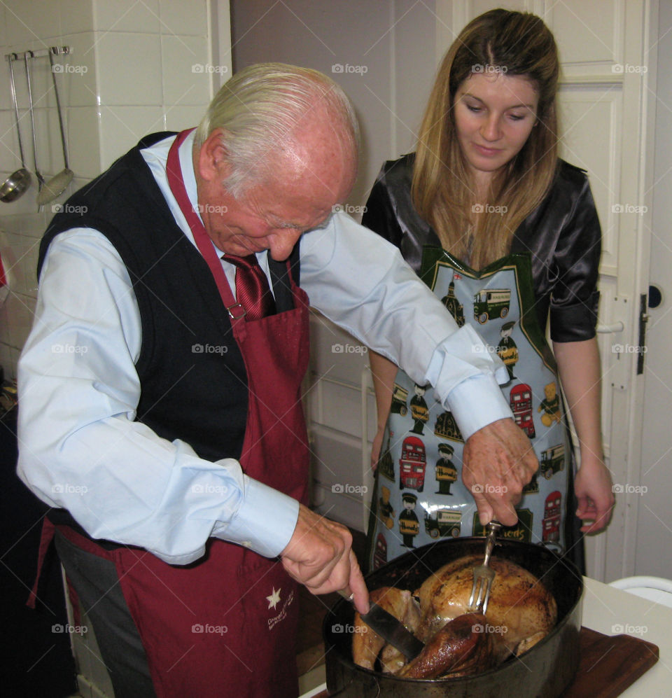 Senior man preparing chicken with his daughter