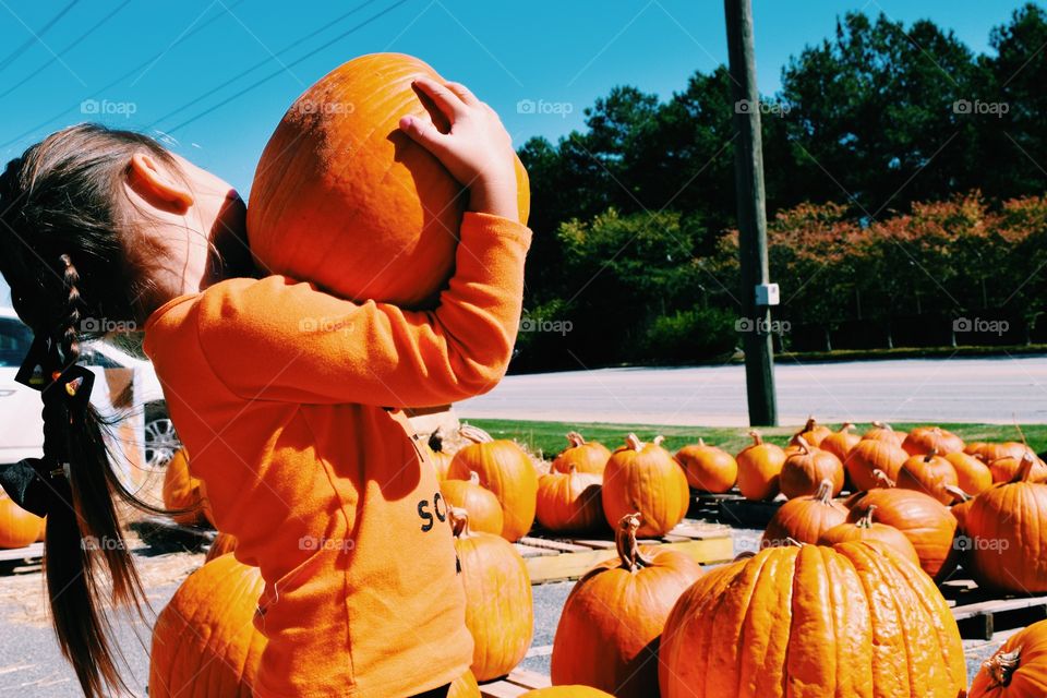Little girl holding pumpkin
