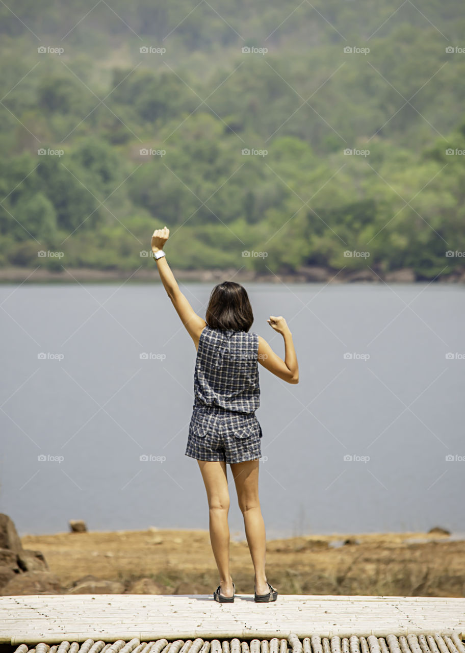 Women raise their arms Background mountains and water at Chakrabongse reservoir , Prachinburi in Thailand.