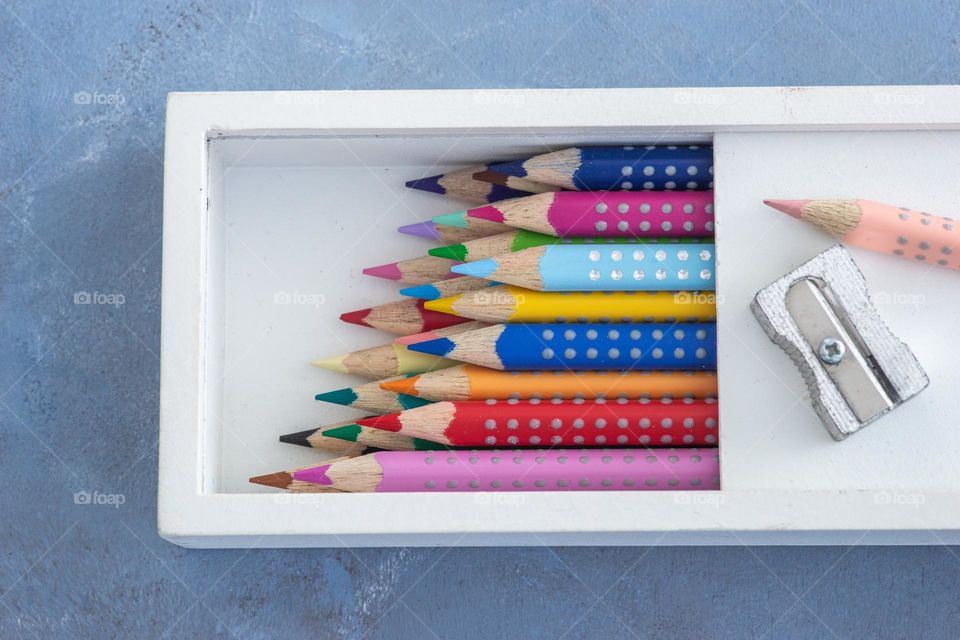 close up of colorful pencils in a wooden box and a metal sharpener