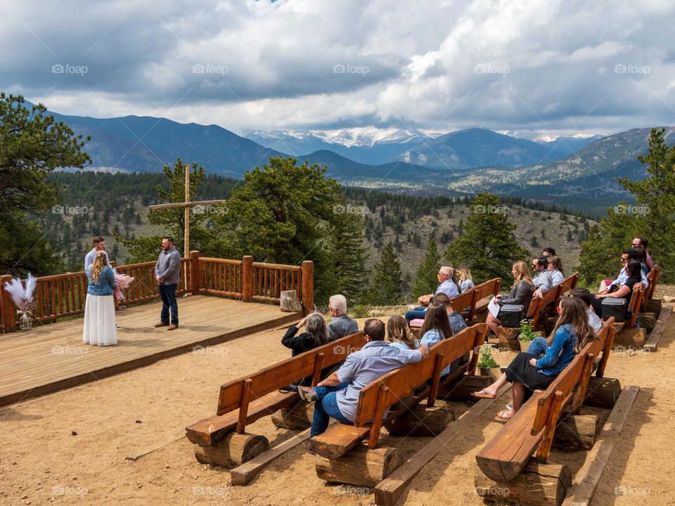 A young couple gets married at an outdoor area set up with an alter and amazing mountain scenery