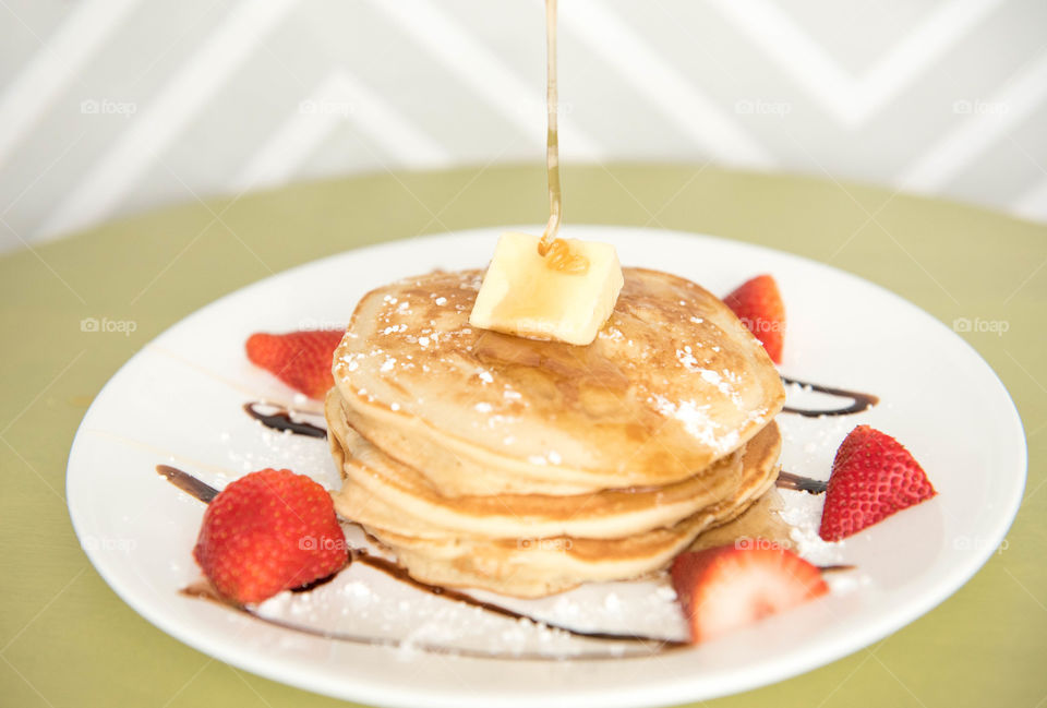 Stack of pancakes with honey being drizzled over the top