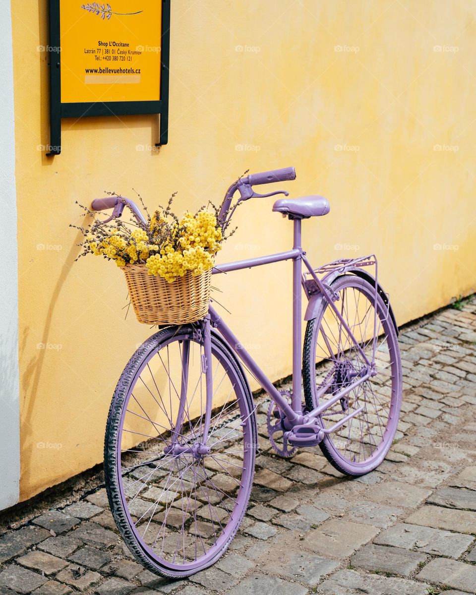 Violet bike in front of a yellow house 