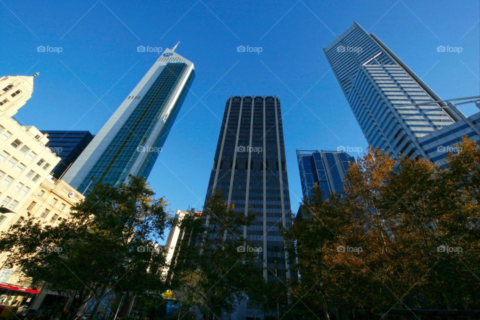 looking up at high rise sky scraper tower buildings rising up into the blue sky in Perth, Western Australia