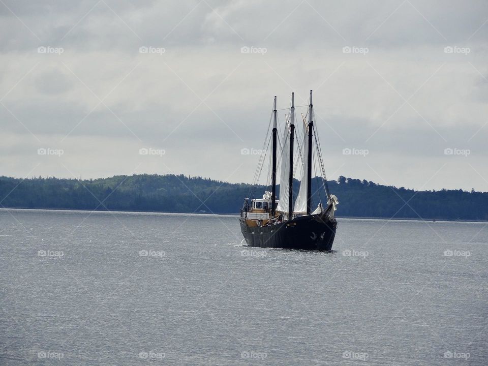 Tall ship in the water surrounding port of Halifax , cloudy day 