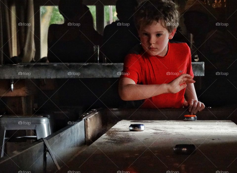 Playing Shuffleboard. Boy Playing Indoor Shuffleboard
