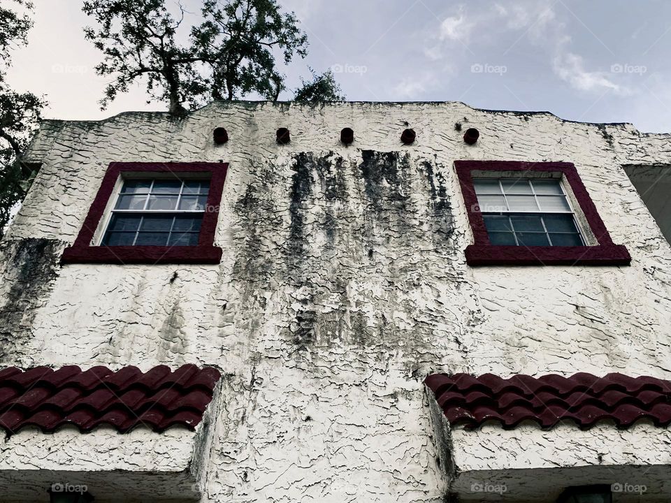 Symmetrical of side of white and red spanish old style architecture residential large house built in the early 1900s. Sign of aged structure with windows looking up to the sky.