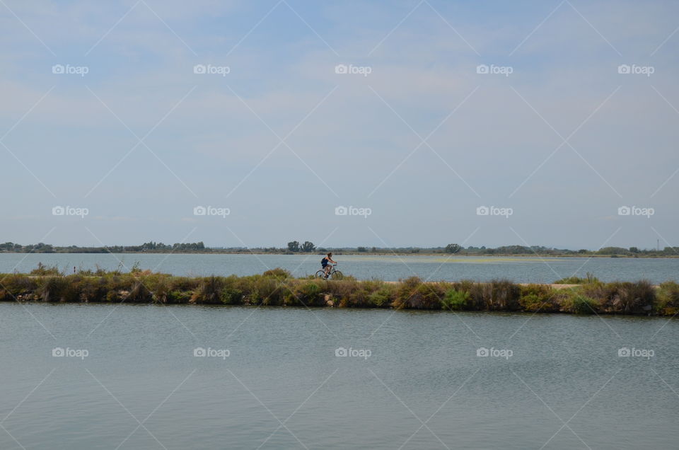 ride a bike between a lake and the Mediterranean Sea to relax without anyone around, enjoying the sea air