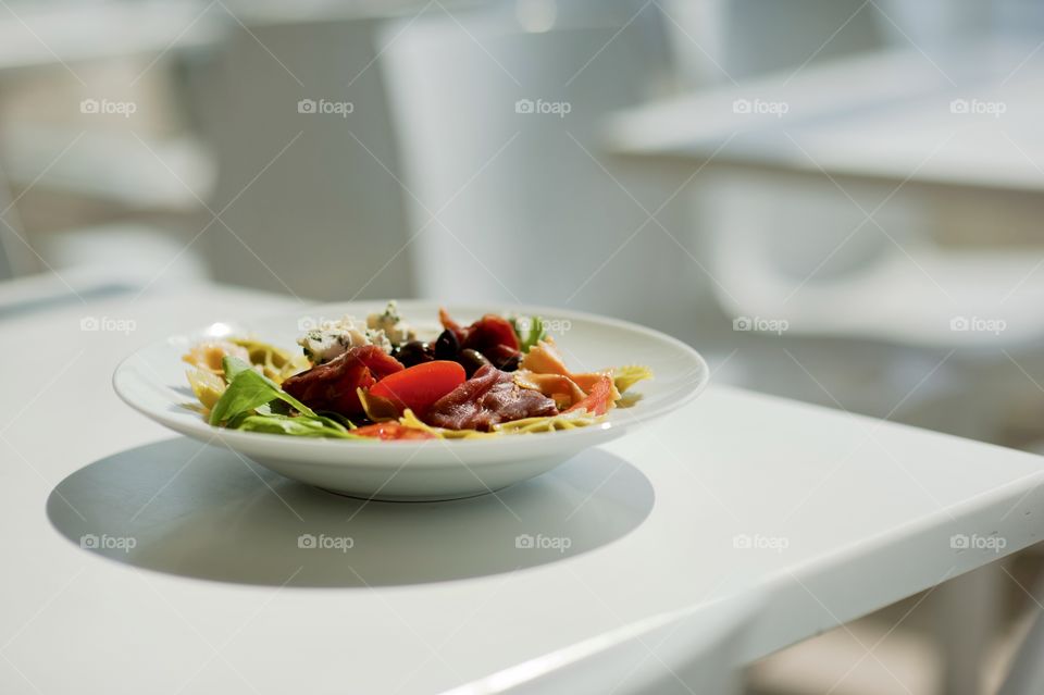 close-up of a young man eating a salad in a light kitchen