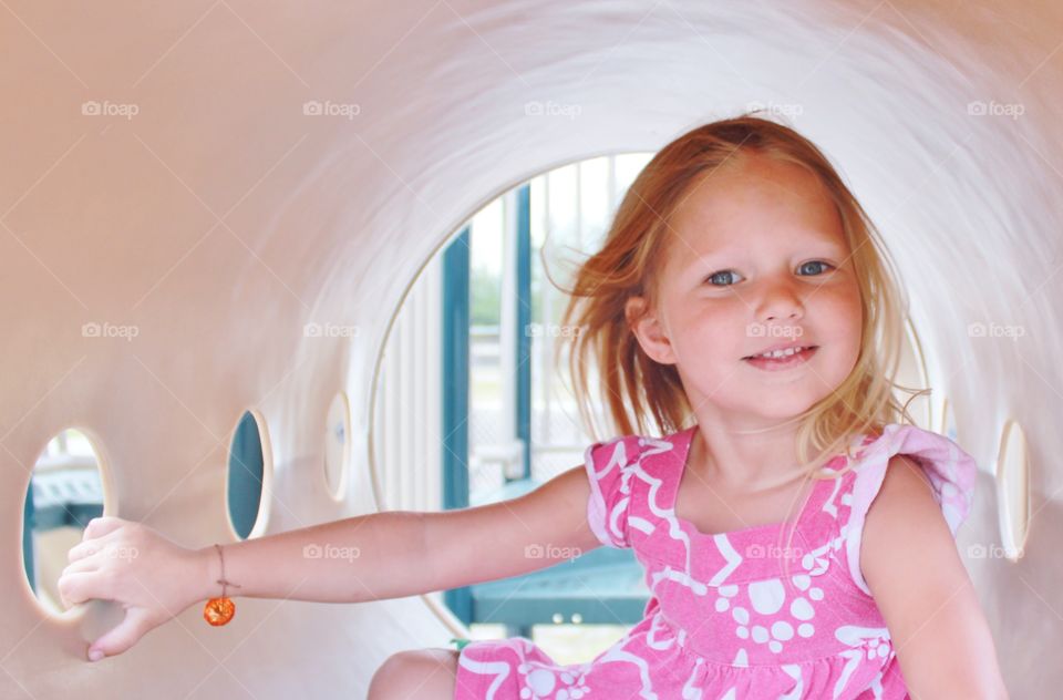 Portrait of a happy girl sitting in tunnel at playground