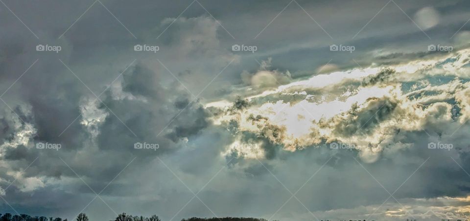 Sunshine through stormy clouds over winter fields.
