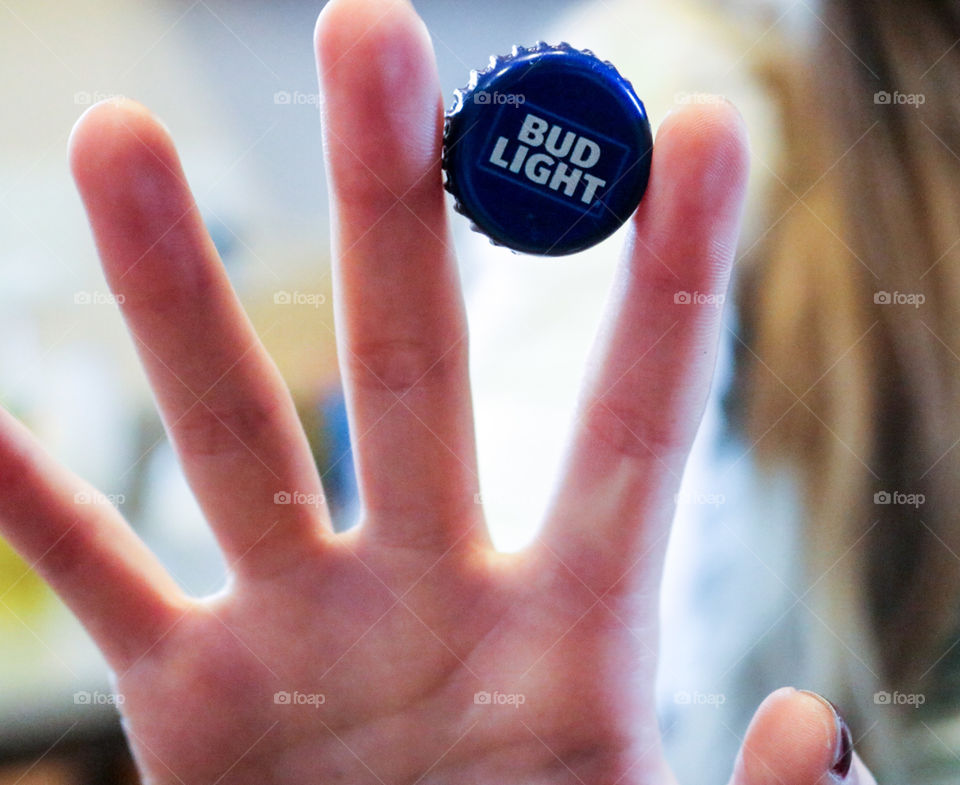 Hive five Bud Light- woman holding bud cap between fingers.