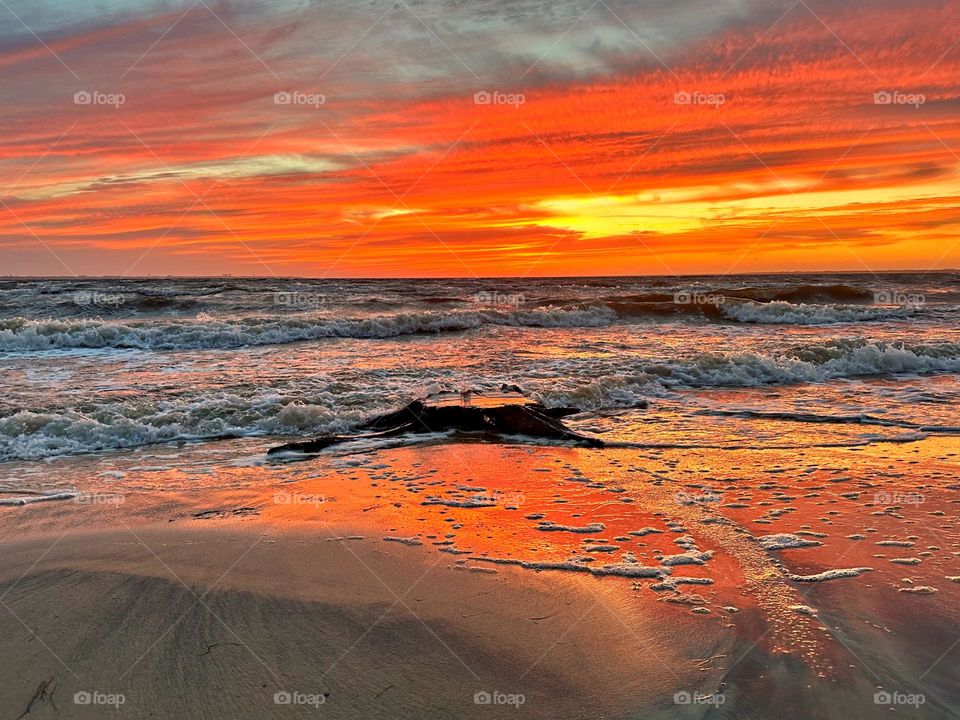 A breathtaking and radiant sunset which colors the waves iridescent, often towers and collides the shore with great force. The impact of the waves against the coastline created a stunning display of energy and motion