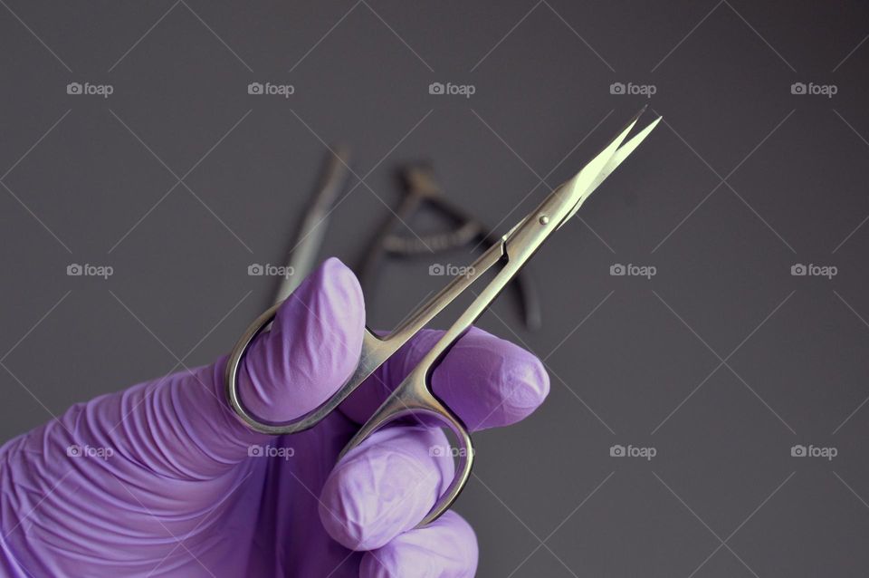 Manicure tools are held by a manicurist in rubber gloves