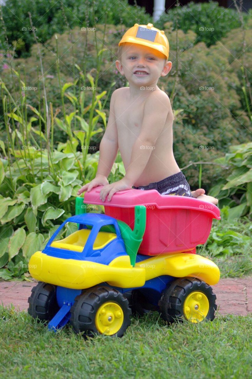 Young boy playing on toy dump truck