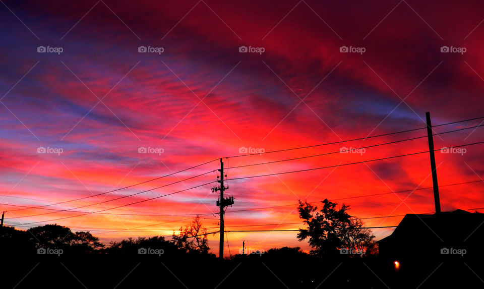 Electricity pole against dramatic sky at sunset