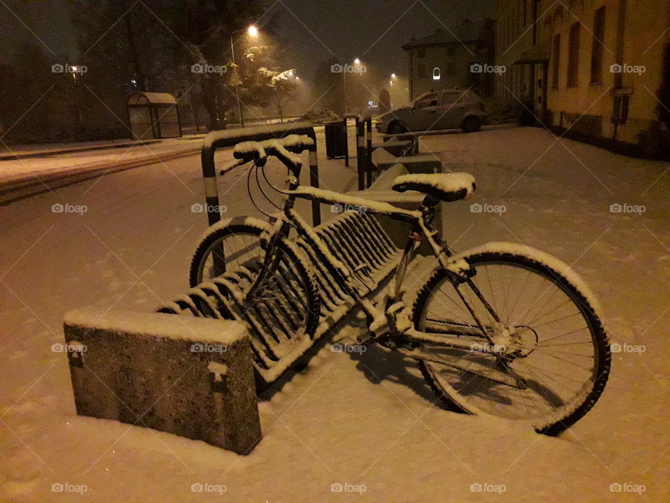 Bicycle under the snow  in the evening..