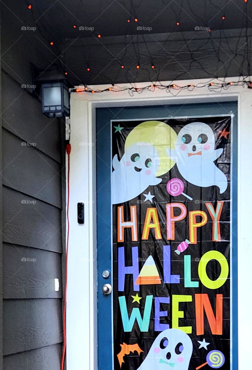 front porch of a suburban home in Oregon decorated for Halloween with a spooky cute door and orange lights