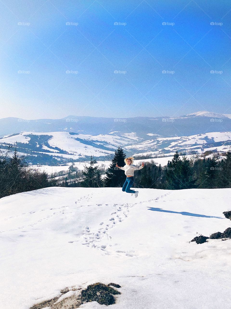 girl jumping from happiness in the snowy mountains