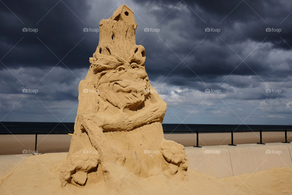 Monster sand sculpture against stormy sky