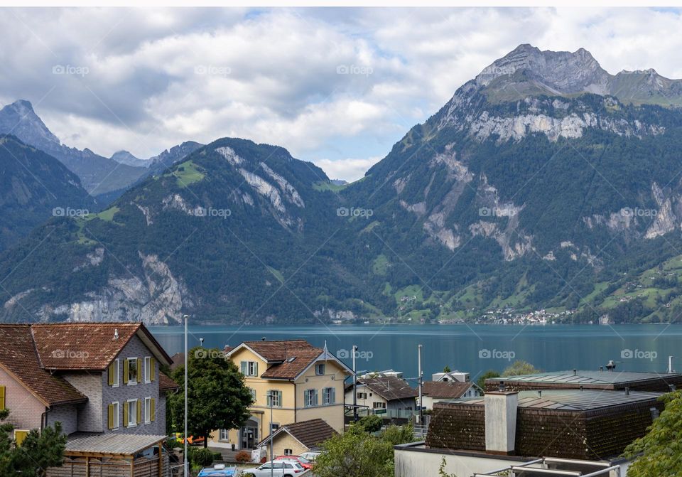 A beautiful view of the stone mountains with residential buildings and a lake between them, close-up side view.