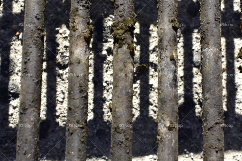 Abstract image of old metal bars with a black stuff coated over it.