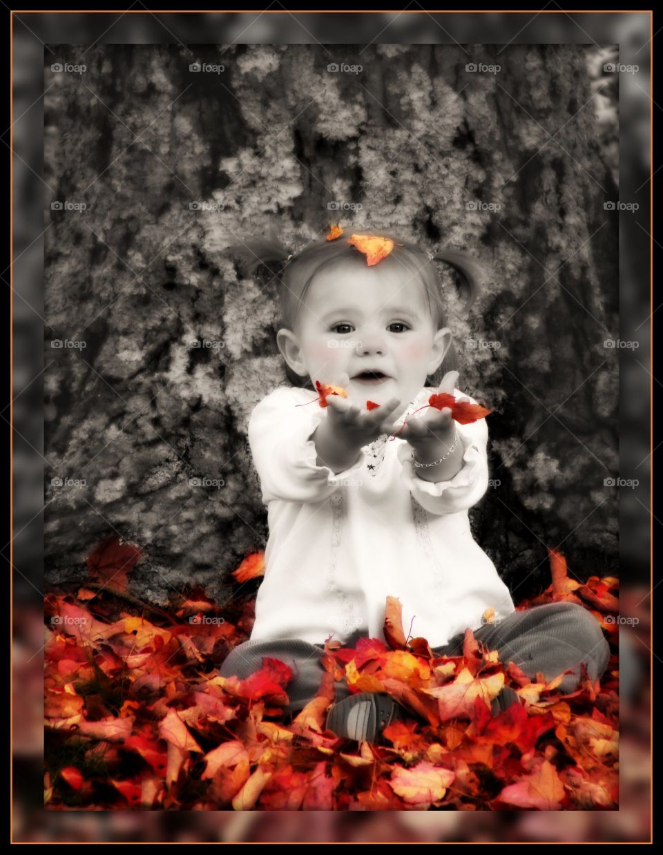 Baby girl sitting surrounded autumn leaf