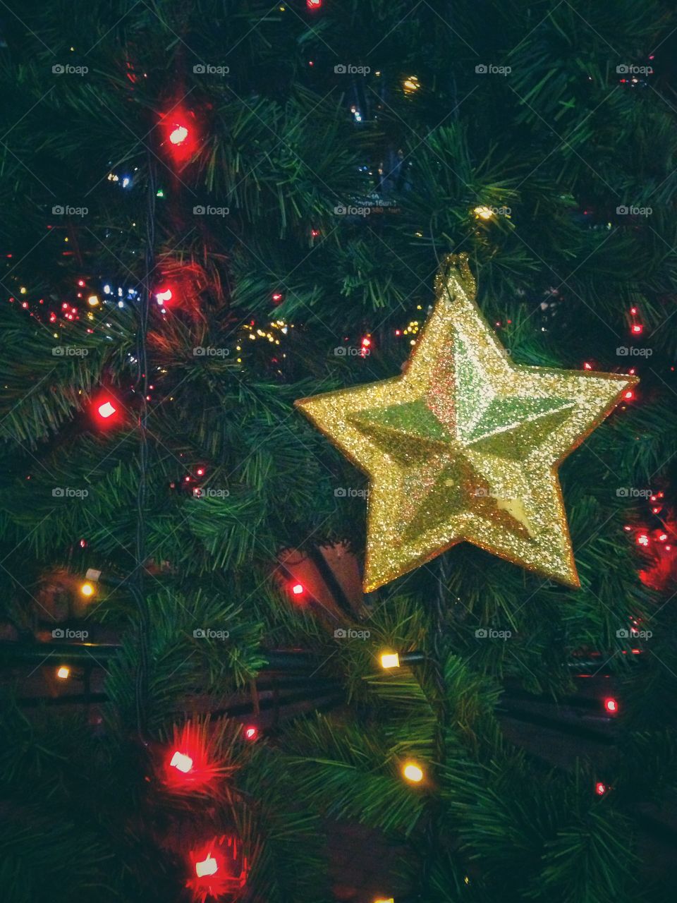 Gold plastic star, balls, red lights garland and other Christmas decorations on artificial fir tree in Moscow, Russia