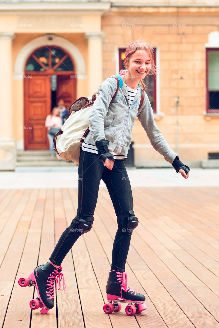 Young girl roller skating in a town spending time actively outdoors on summer day