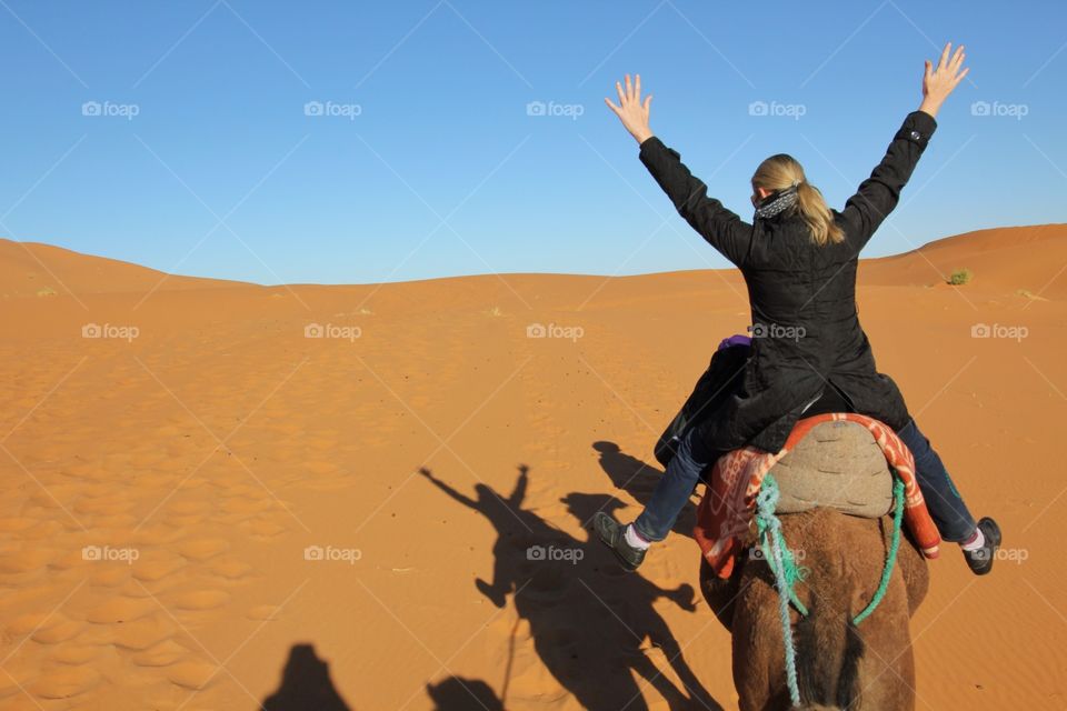 Hands in the air happy to be in the Sahara on a camel 