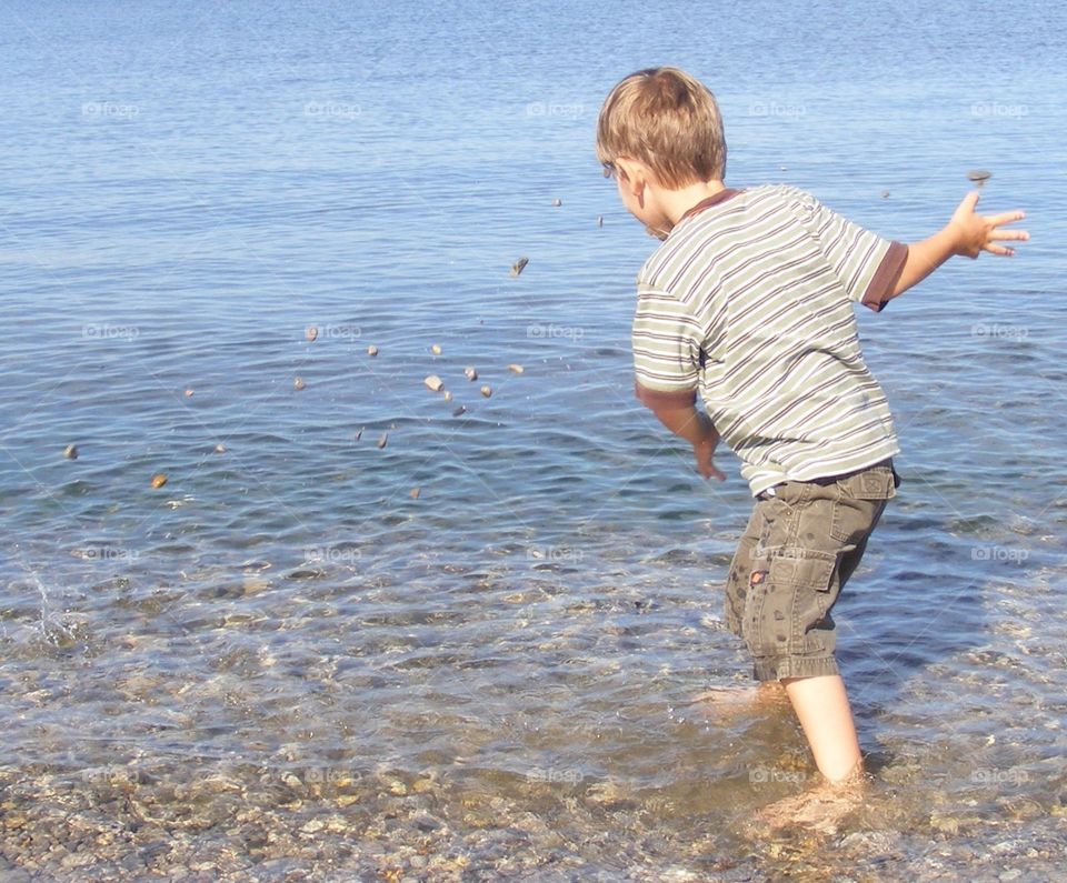 Boy tossing rocks out into the water
