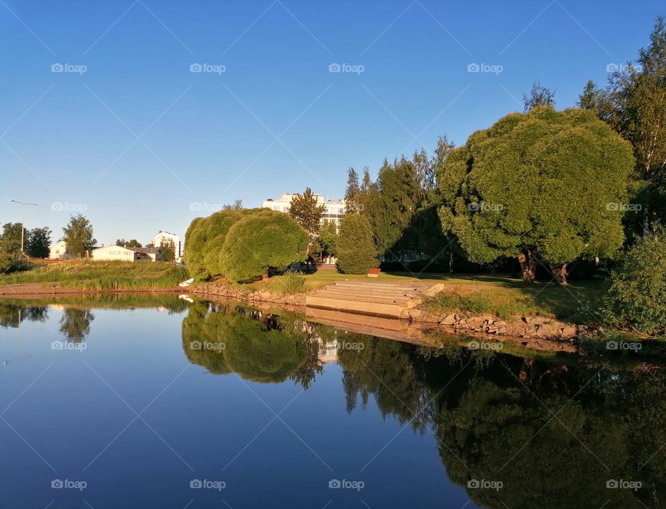 A magnificent image of a calm river with a mirror image of trees and shrubs.